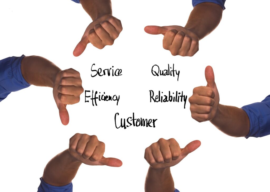 Six hands show thumbs up around the words “Service, Efficiency, Customer, Quality, Reliability” written in black marker on a white background.